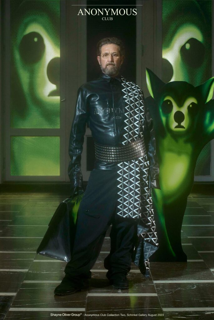 A fitted black leather jacket with a collar and asymmetric design paired with matching pants.