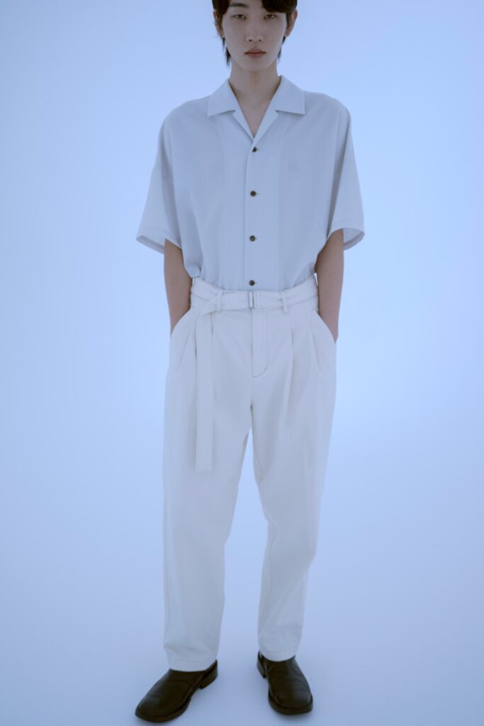 A relaxed white shirt with short sleeves and collared neckline paired with straight-leg pants.