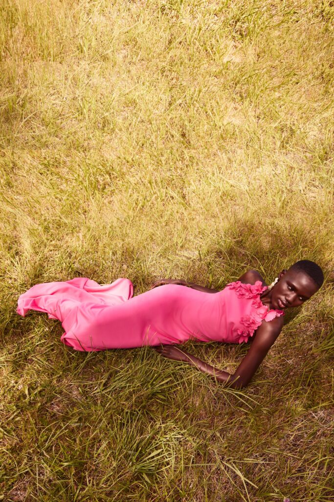 A fitted pink silk sleeveless dress with a V-neckline and ruffled detailing.