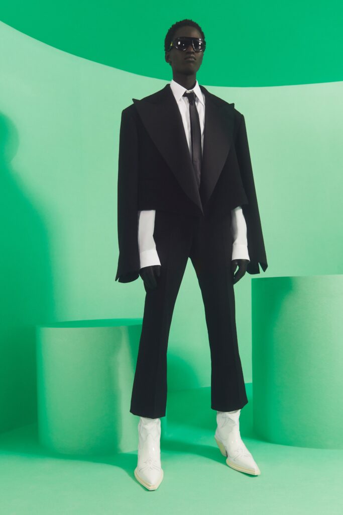 A black tailored jacket with white shirt and pants, complemented by stylish footwear.