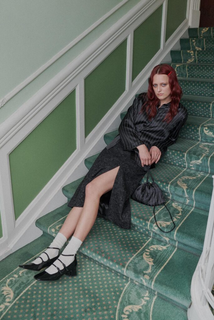 A fitted black silk dress with a V-neckline and a stylish slit detail.
