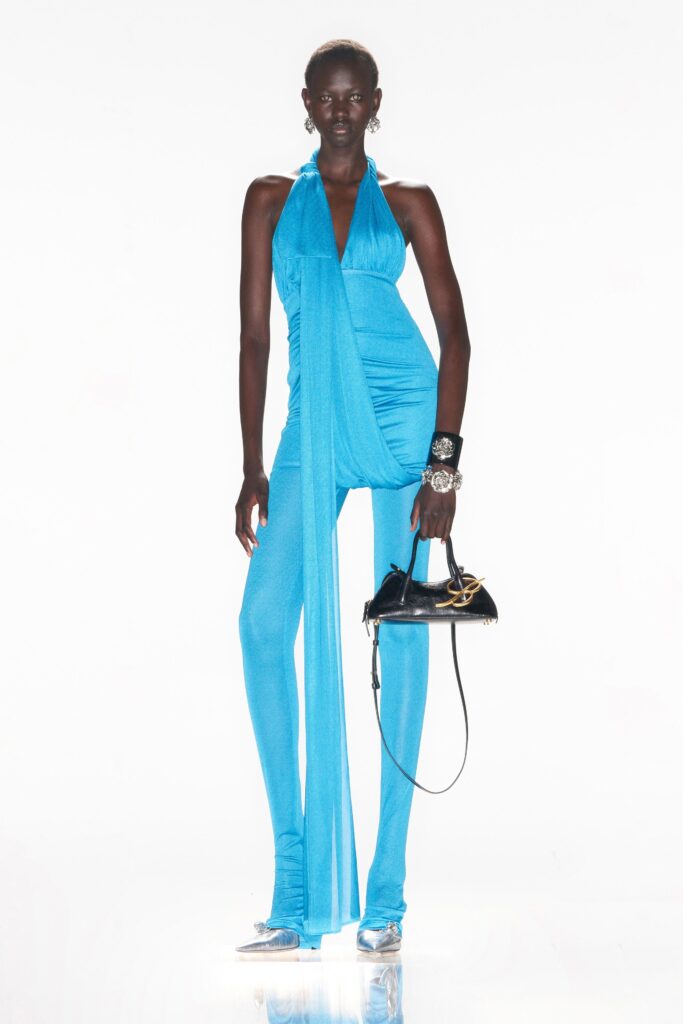 A fitted blue silk halter jumpsuit with a draped design for a striking silhouette.