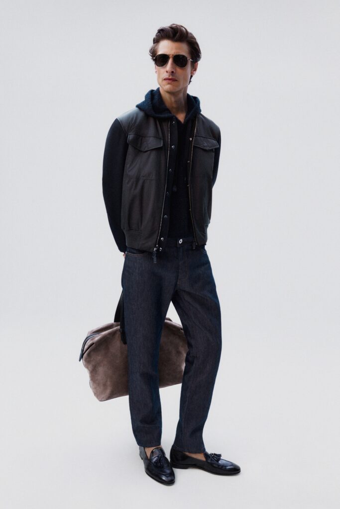 A relaxed black leather jacket with a collared neckline paired with gray denim pants.