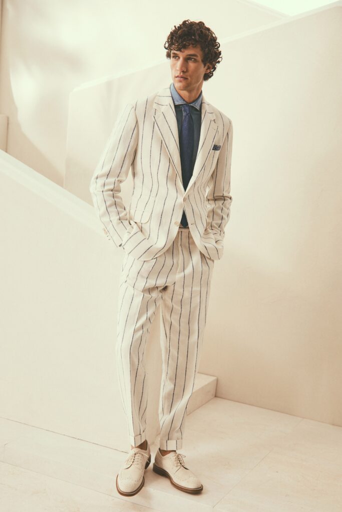 A tailored white suit with blue stripes and a collared shirt, perfect for formal occasions.