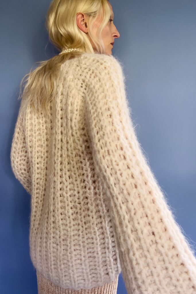 An oversized beige wool sweater with long sleeves and a knitted texture.