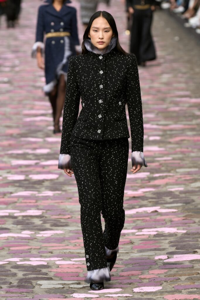 A fitted black silk suit with long sleeves and embroidered details, perfect for formal occasions.