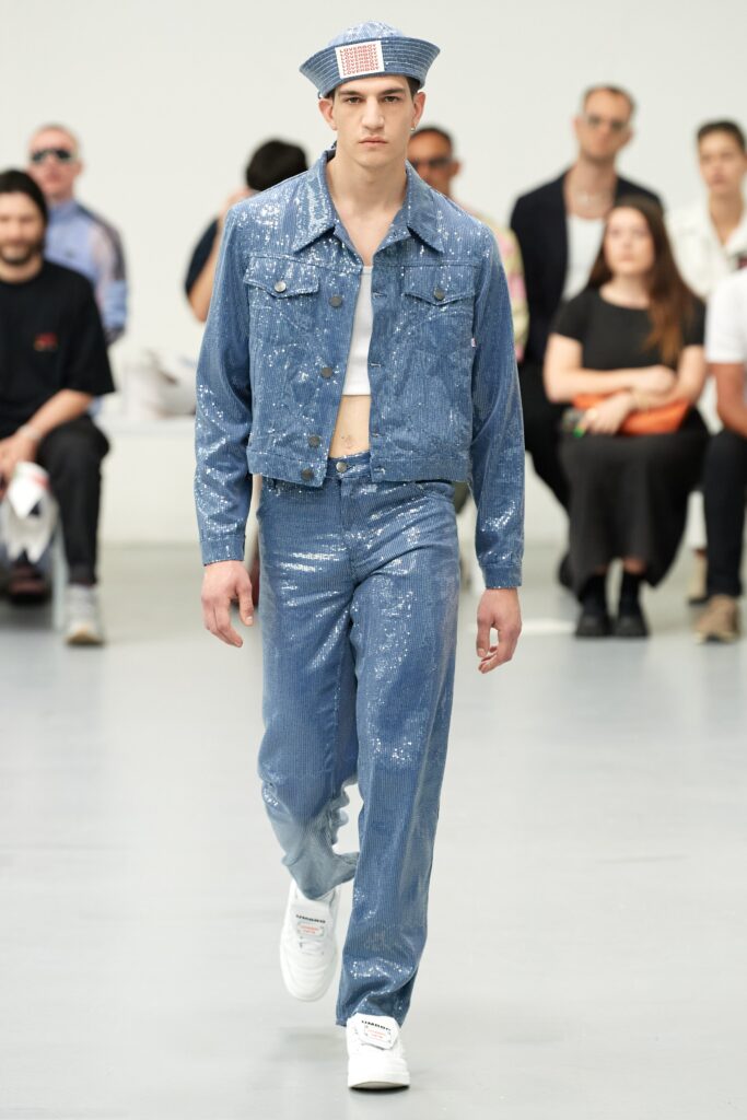 A fitted blue denim jacket with long sleeves and matching pants featuring a zippered detail.