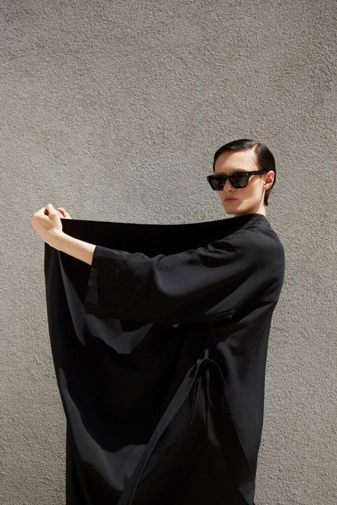A relaxed black silk coat with long sleeves and an asymmetric design.