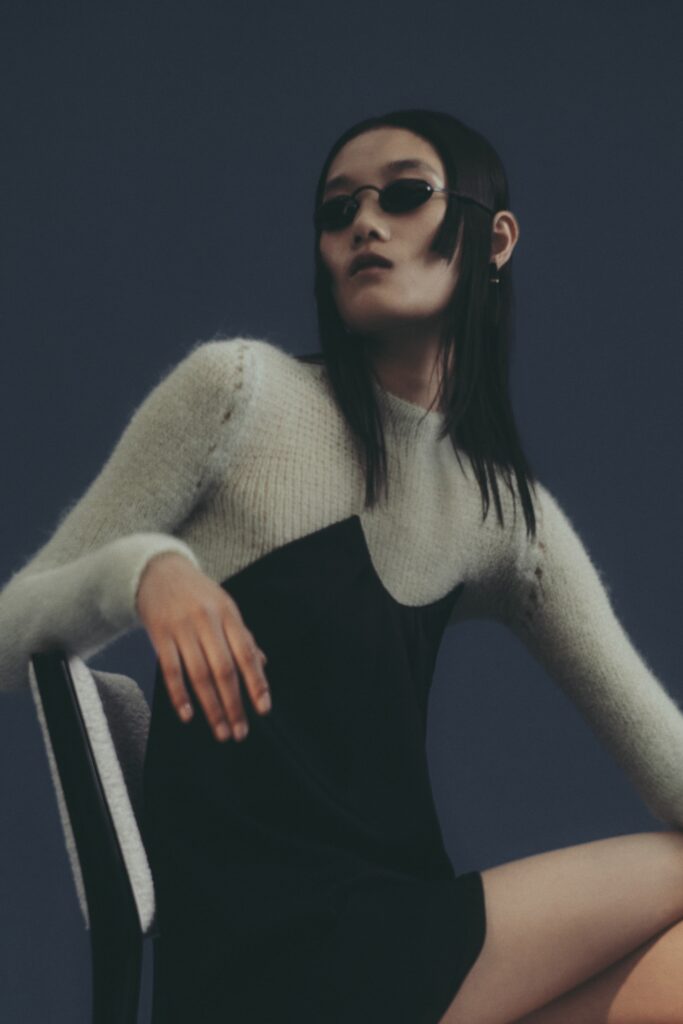 A fitted black dress layered with a gray long-sleeve sweater featuring a V-neckline.