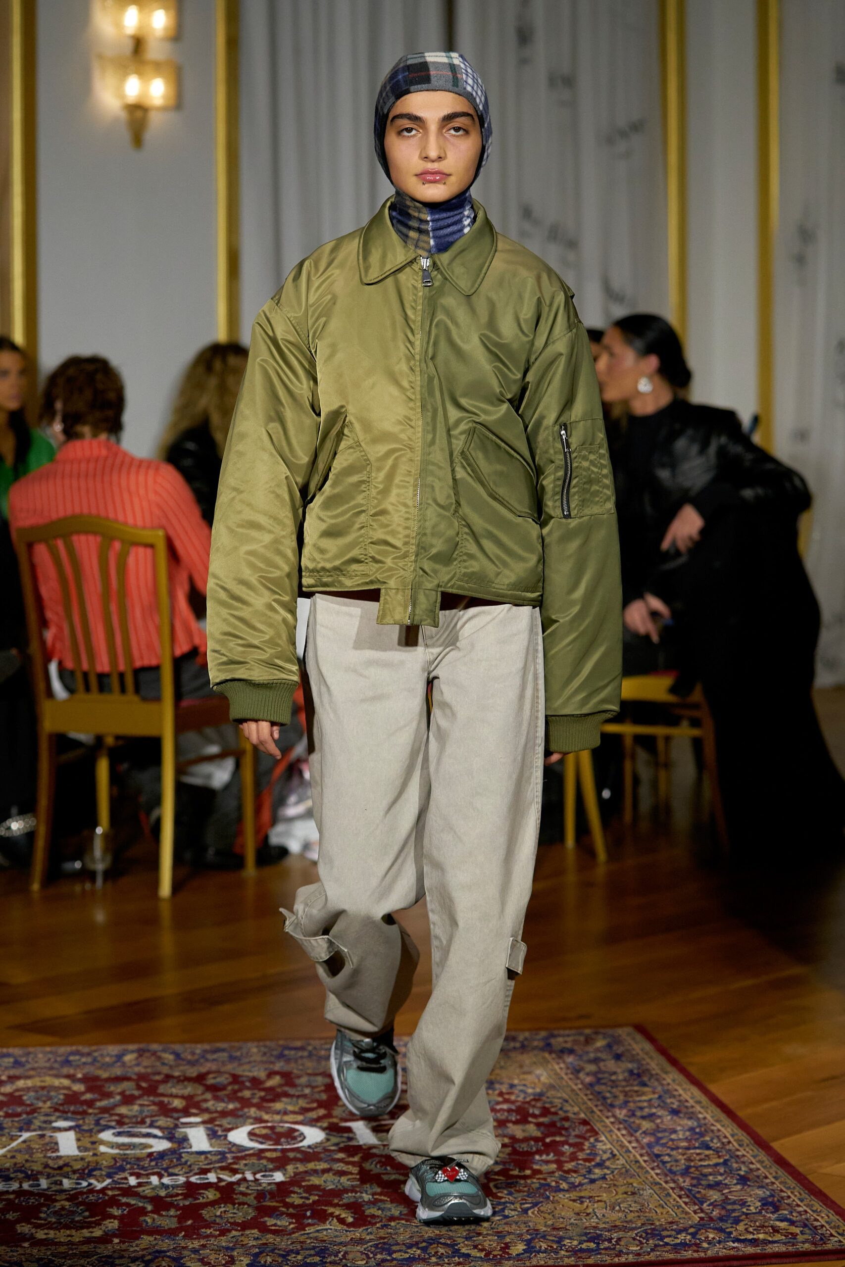 A relaxed green jacket paired with beige pants, featuring a zippered detail and long sleeves.