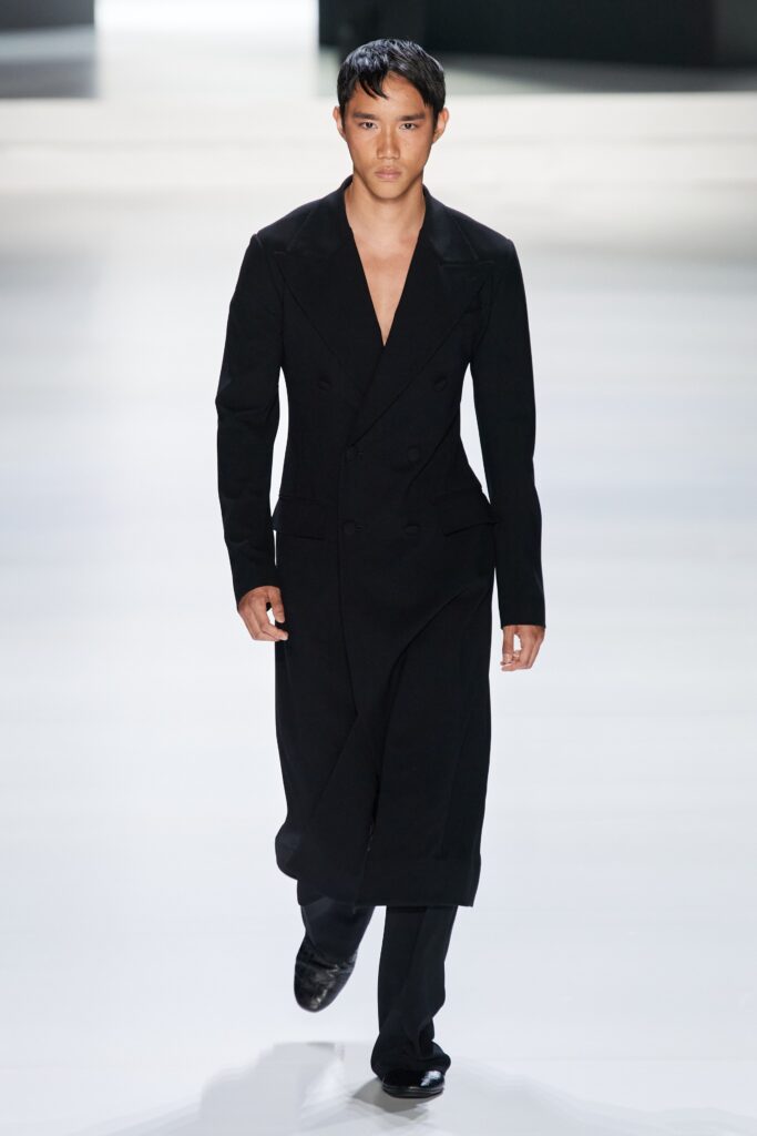 A fitted black wool coat with a V-neckline and double-breasted design.