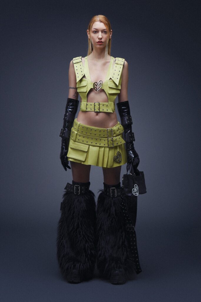 A fitted green leather sleeveless top and pleated skirt with zippered details.