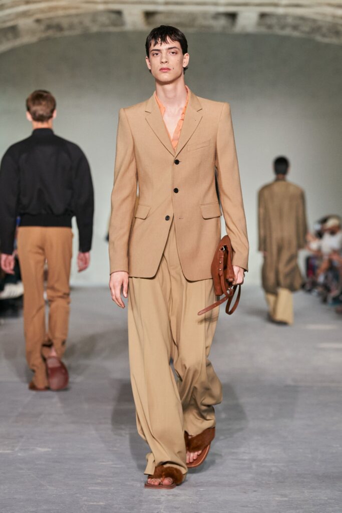 A tailored beige suit with long sleeves and a collared design featuring straight-leg trousers.