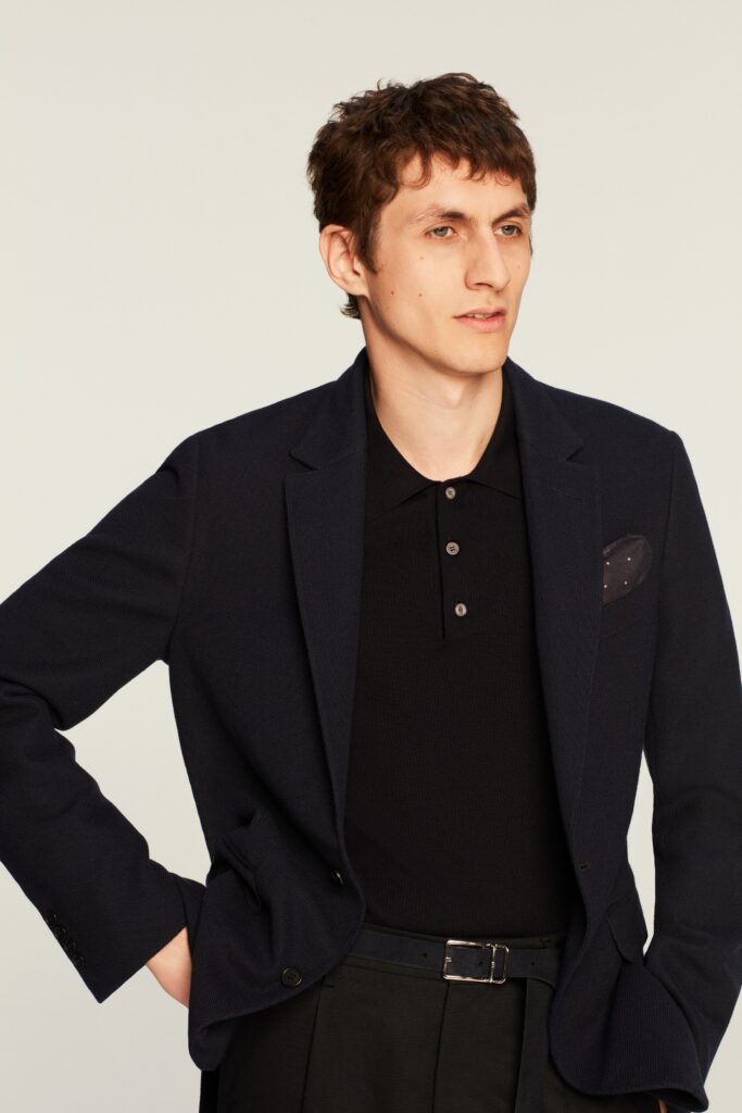 A fitted navy blazer paired with a black collared shirt, featuring a buttoned design.