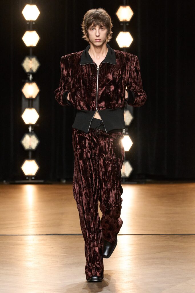 A fitted burgundy velvet jacket with a collared neckline paired with straight-leg pants.