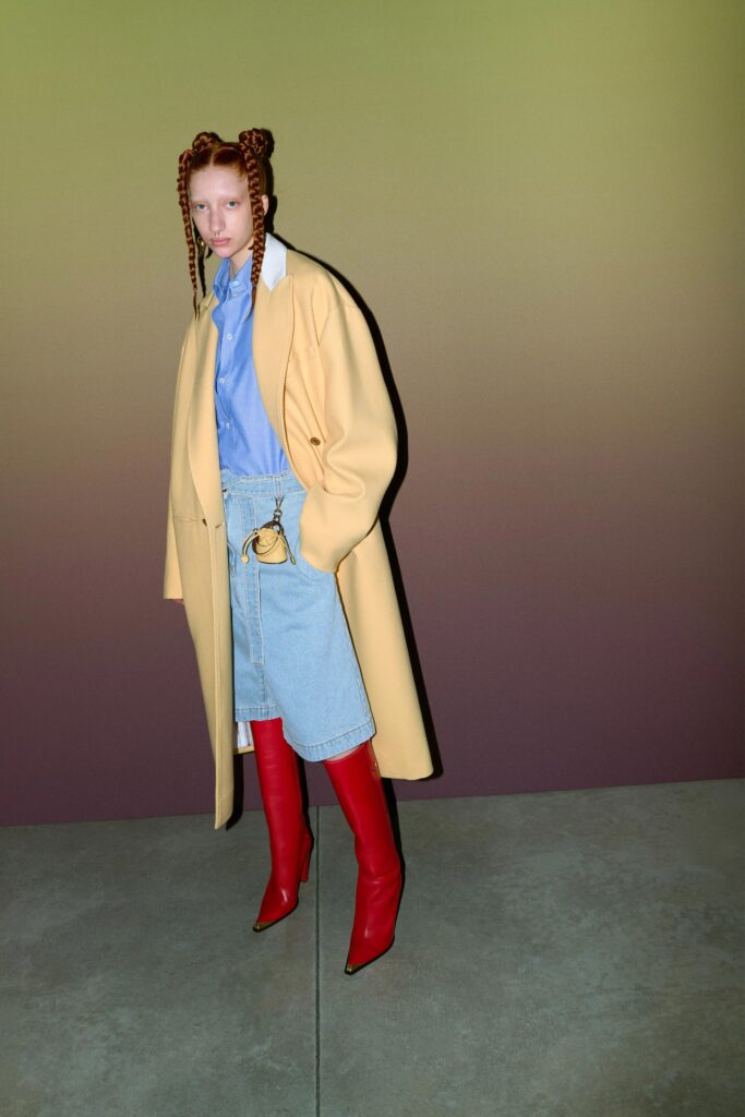 A relaxed yellow coat paired with a blue collared shirt and an asymmetric denim skirt.