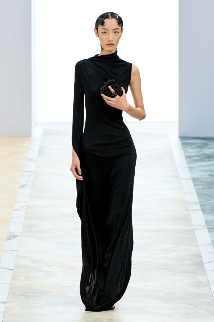 A fitted black silk dress with a sleeveless design and asymmetric silhouette.