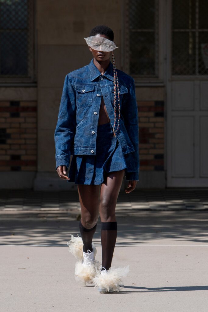 A fitted blue denim jacket with a pleated skirt, showcasing a stylish and modern look.