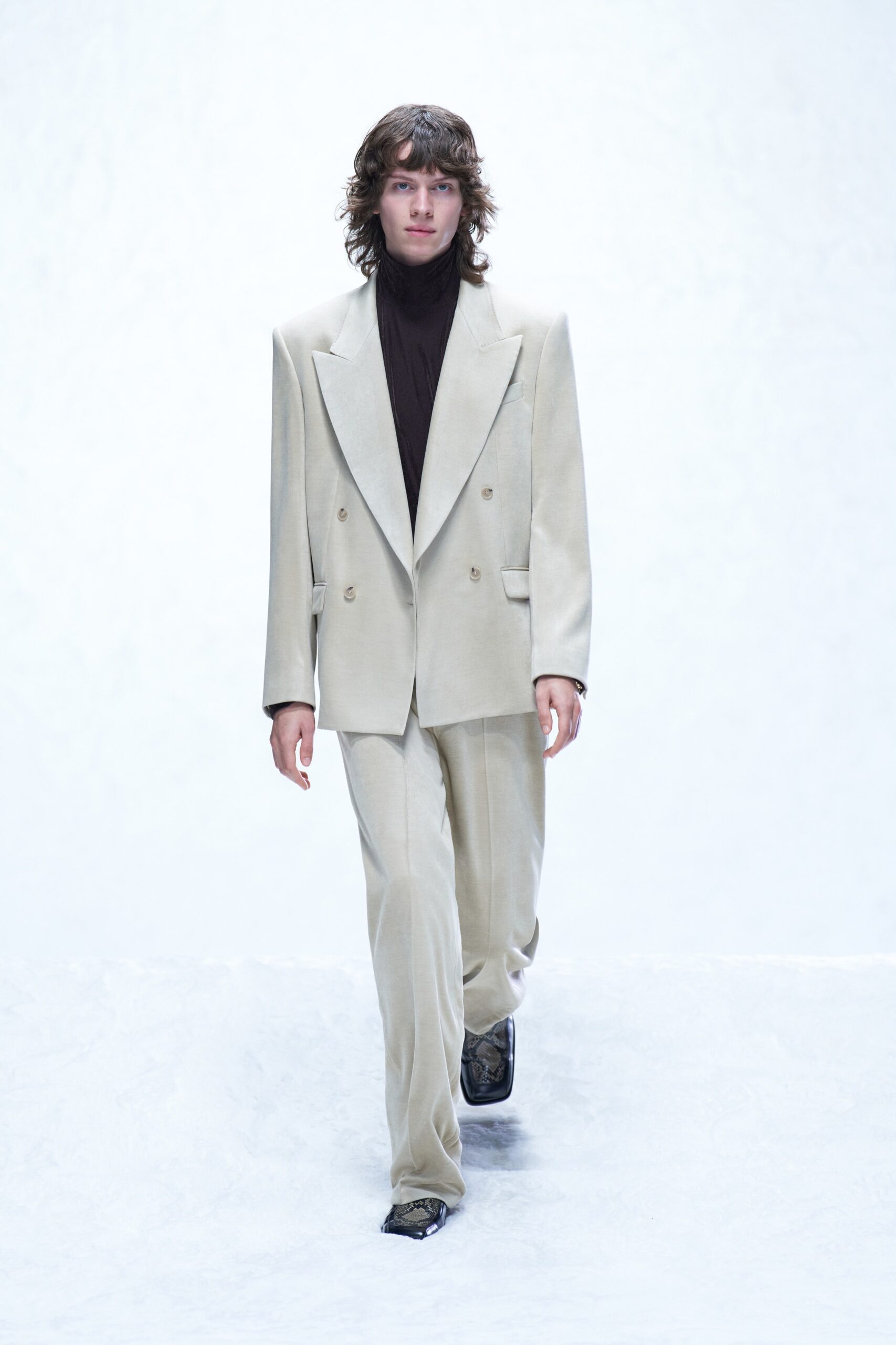 A tailored beige wool suit featuring a long-sleeve collared jacket and double-breasted design.