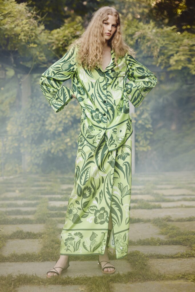 A relaxed green silk dress with long sleeves and a collared neckline featuring a vibrant print.