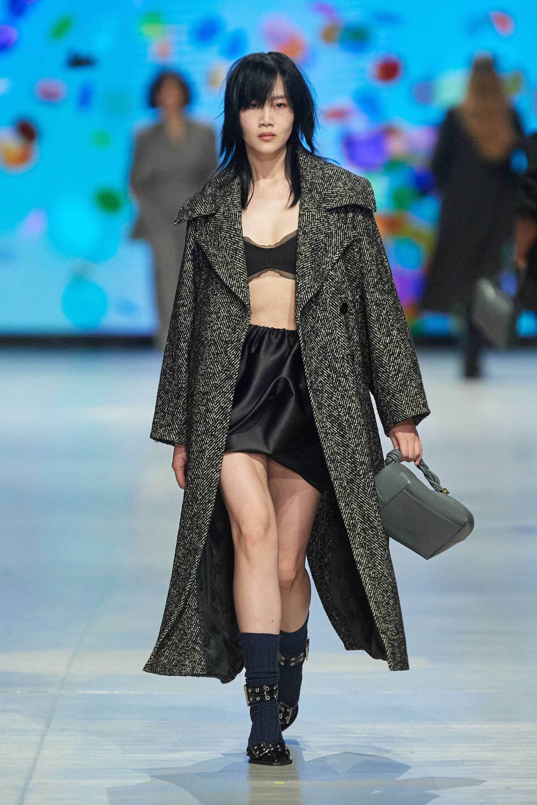 A fitted black wool coat layered over a sleek skirt with an asymmetric design.