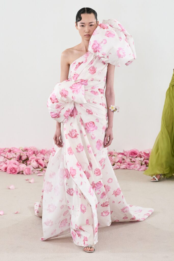 A fitted white dress with pink floral patterns, featuring an off-shoulder design and flared silhouette.