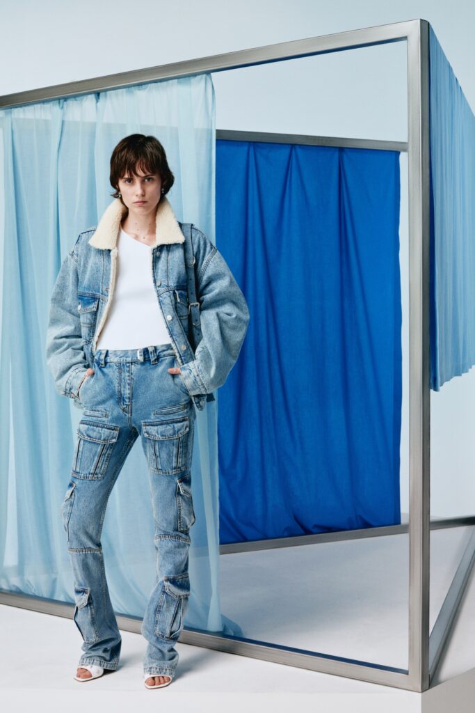 A fitted blue denim jacket with a collared neckline paired with flared denim pants.