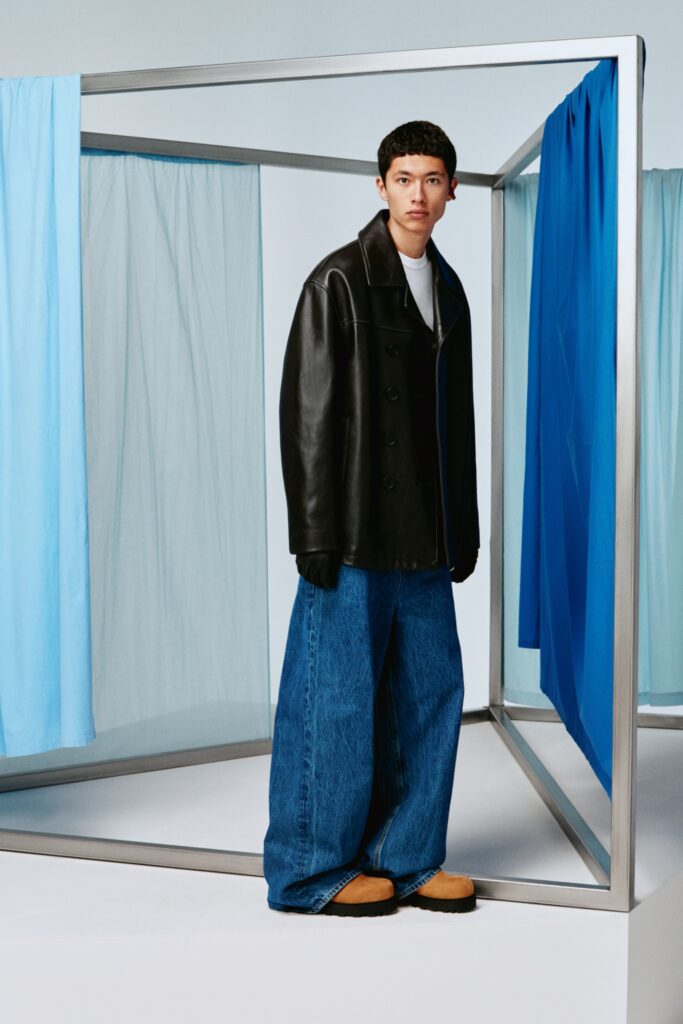 A relaxed black leather jacket paired with wide-leg blue denim pants.