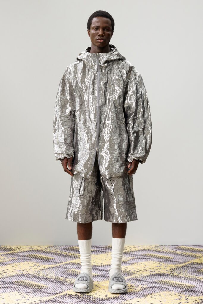 A relaxed fit silver metallic hooded jacket paired with matching shorts featuring a zippered closure.