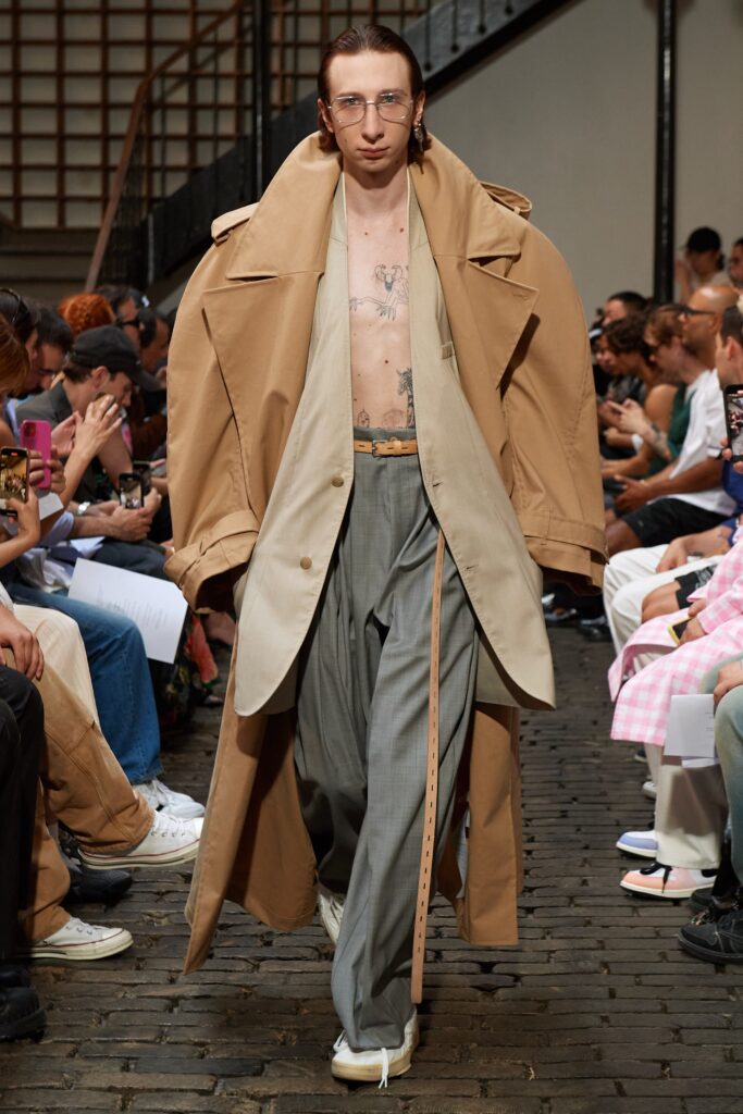 A relaxed beige coat layered over gray wide-leg pants, featuring a collared design.