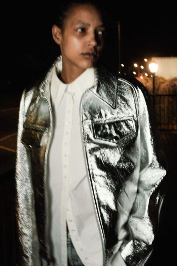 A relaxed silver denim jacket layered over a white collared shirt with button details.