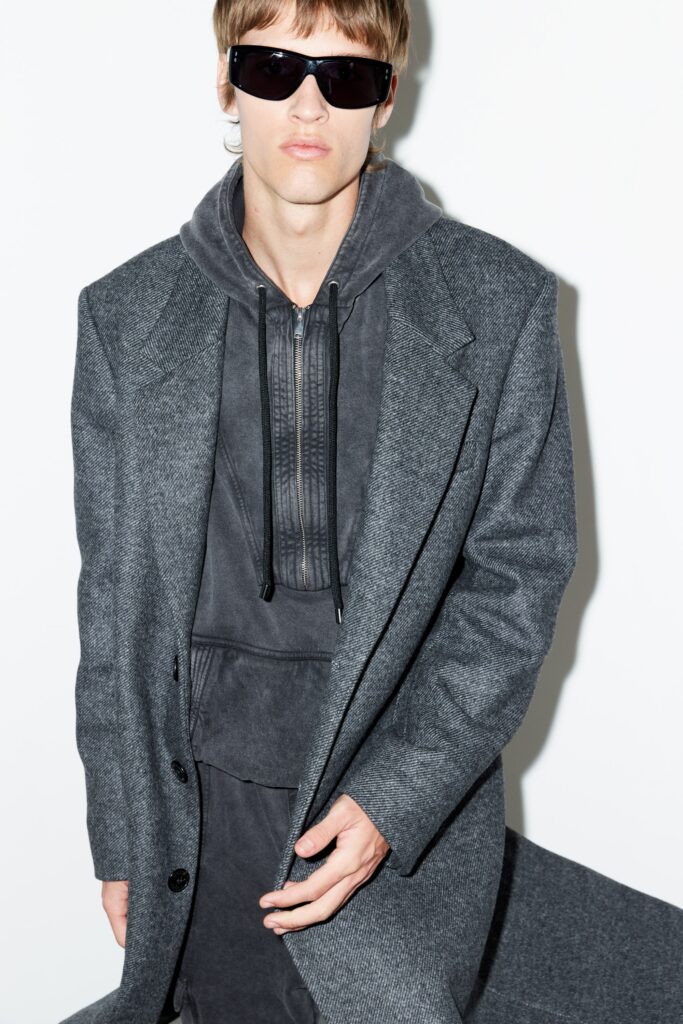 A relaxed gray coat layered over a hooded sweatshirt, combining comfort and style.