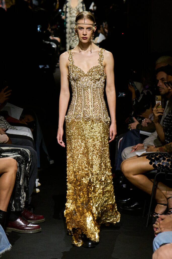 A fitted gold sequin gown with a V-neckline and tiered design details.