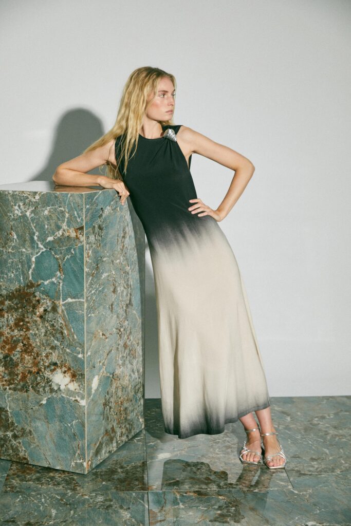 A fitted sleeveless dress featuring a high-neck design with an ombre effect from black to cream.