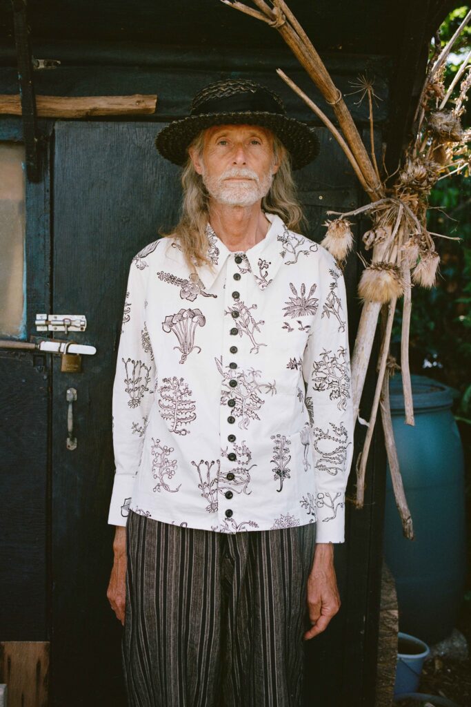A relaxed white cotton long-sleeve shirt with a printed design paired with striped pants.