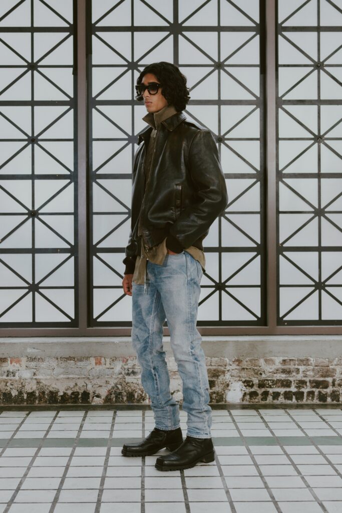 A fitted black leather jacket paired with straight-leg blue denim pants.