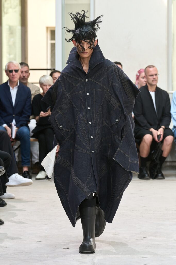 An oversized blue denim coat with long sleeves and an asymmetric design.