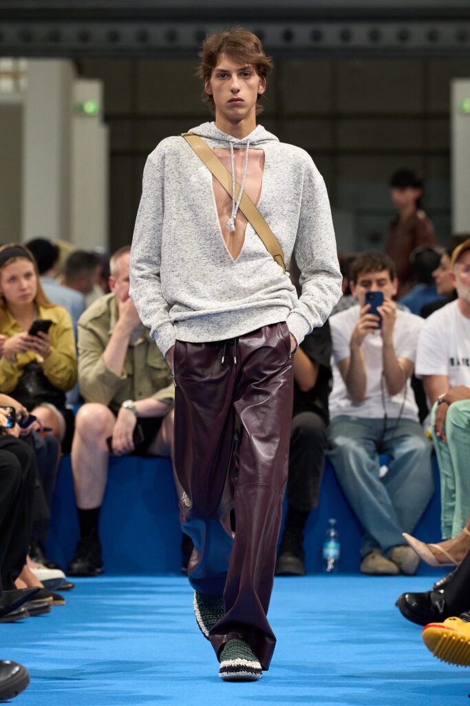 A relaxed gray long-sleeve sweater with a V-neck and asymmetric design paired with burgundy pants.