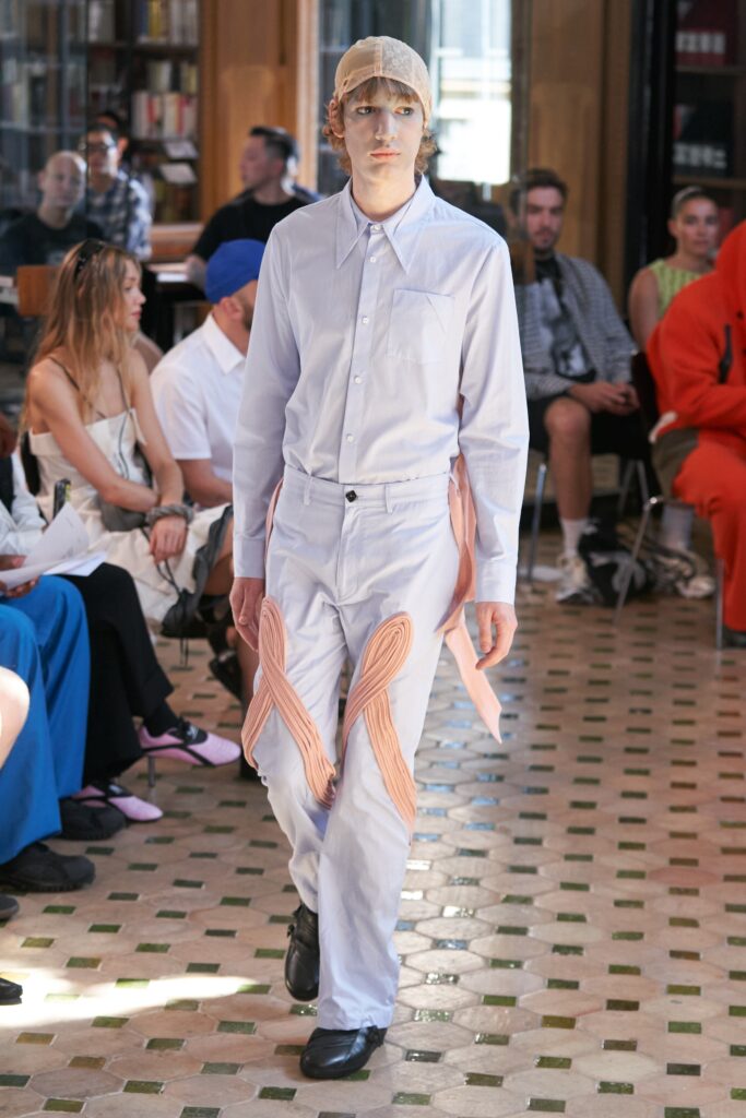 A relaxed white long-sleeve collared shirt paired with beige pants featuring an asymmetric design.