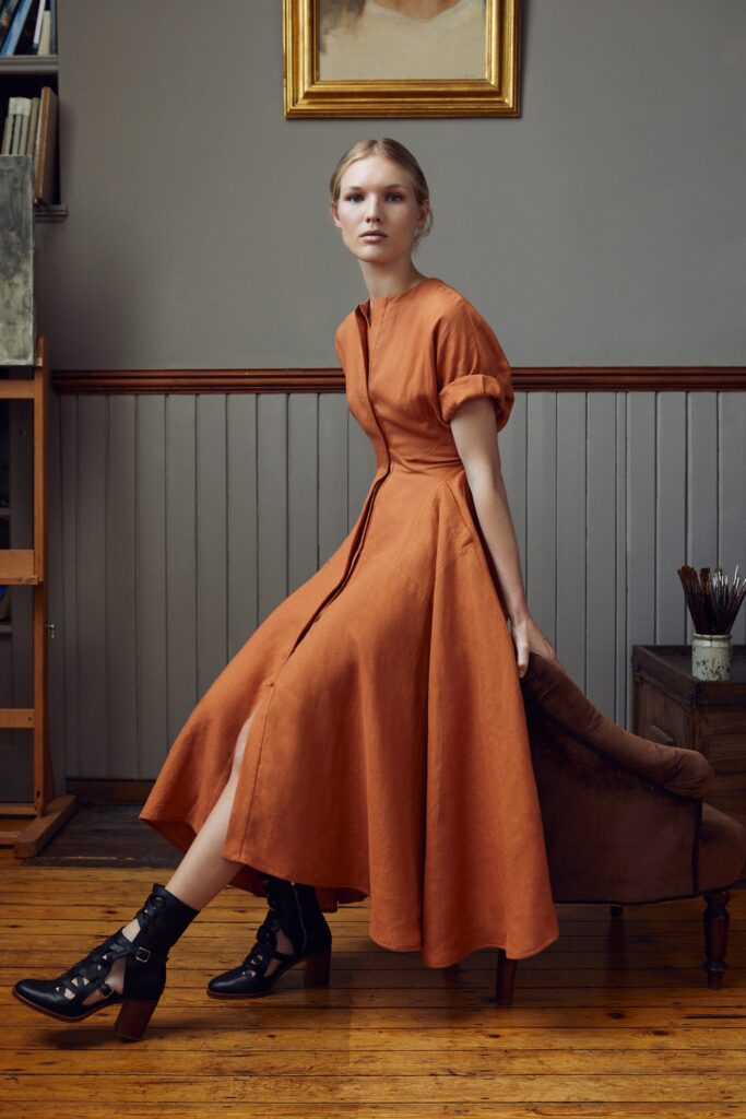 A fitted orange cotton dress with short sleeves, a V-neckline, and an A-line silhouette.