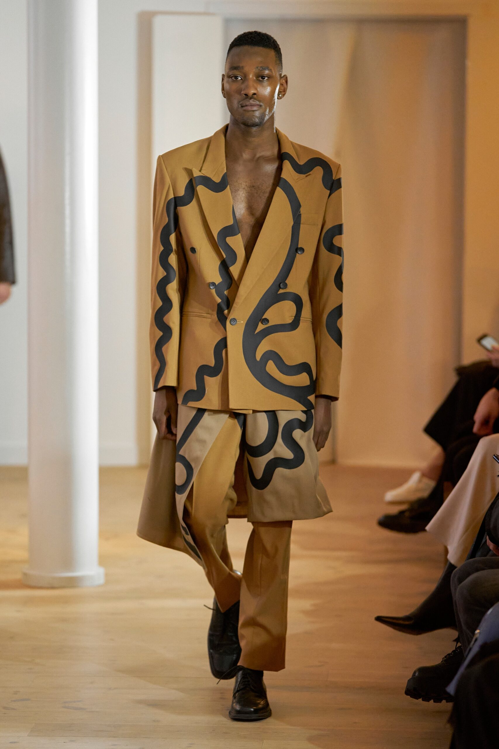 A fitted brown suit with a printed design and long sleeves, featuring a collared neckline.