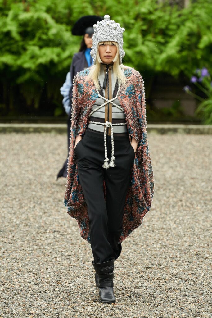 A relaxed multicolor cape paired with black pants, featuring a long-sleeve and collared design.
