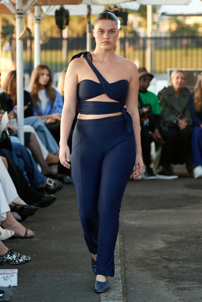 A fitted blue sleeveless top with an asymmetric design paired with matching fitted pants.