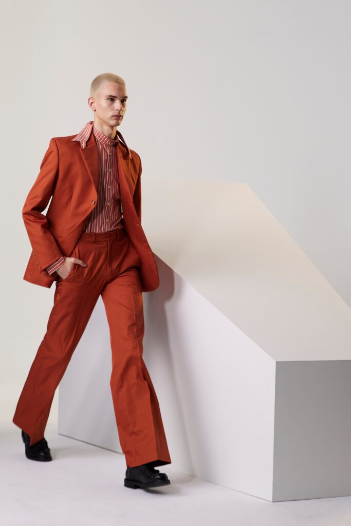 A tailored orange suit with a long-sleeve collared shirt and flared trousers.
