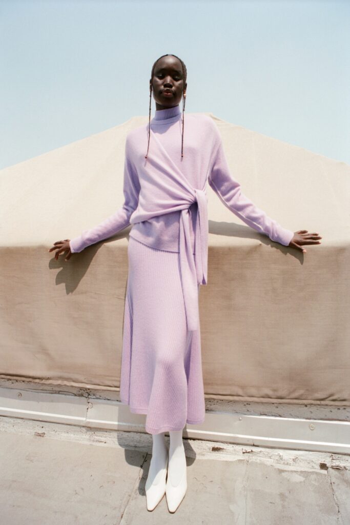 A fitted purple knit dress with long sleeves and an asymmetric design.
