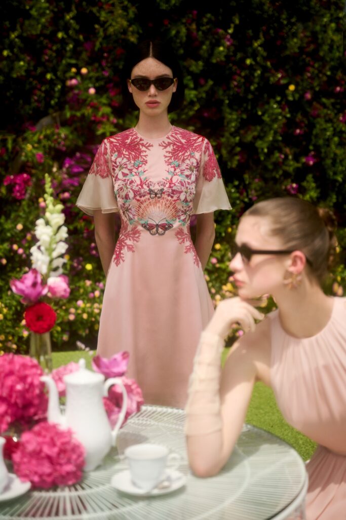 A fitted pink silk dress with short sleeves and intricate embroidery details.
