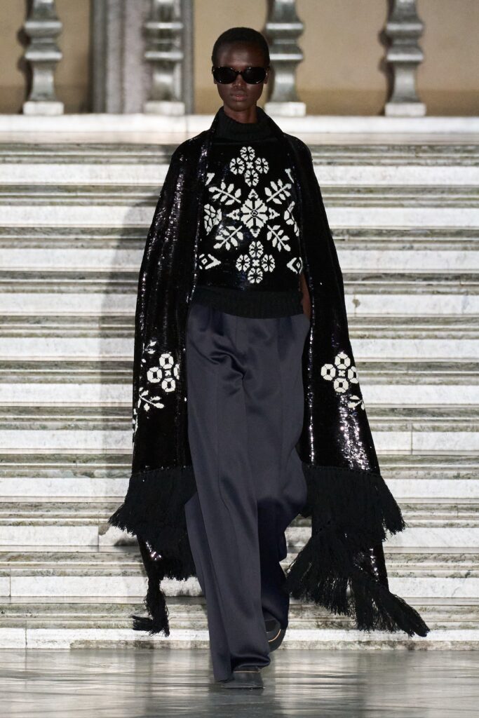A relaxed black embroidered sweater paired with wide-leg pants for a chic runway look.