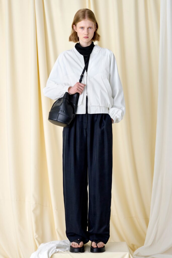 A relaxed white cotton jacket with long sleeves paired with black pants, creating a chic ensemble.