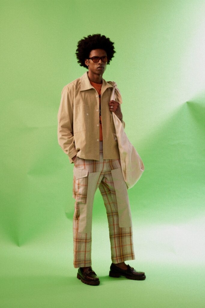 A relaxed beige cotton jacket with a collared neckline paired with plaid pants.