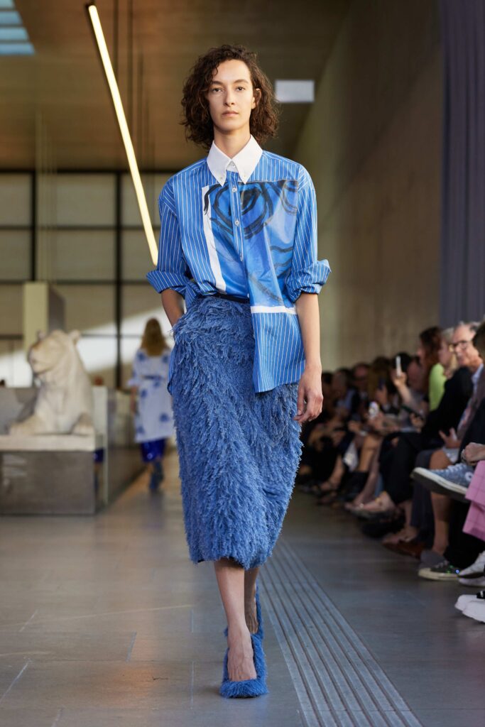A fitted blue cotton long-sleeve shirt paired with a textured fur skirt.